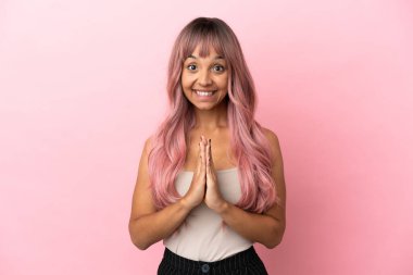 Pembe arka planda pembe saçlı melez bir kadın avuç içlerini bir arada tutuyor. İnsan bir şey ister.