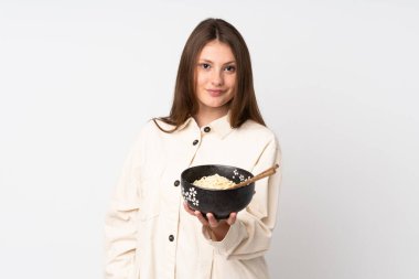 Beyaz arka planda, elinde çubuklarla elinde bir kase şehriye tutarken mutlu bir ifadeyle izole edilmiş beyaz bir kız.