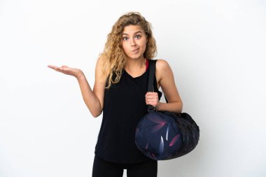 Spor çantalı genç bayan, beyaz arka planda izole edilmiş, kuşkuları olan ve ellerini kaldıran.