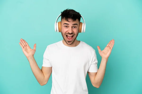 Jovem Caucasiano Isolado Fundo Azul Surpreendido Ouvindo Música — Fotografia de Stock