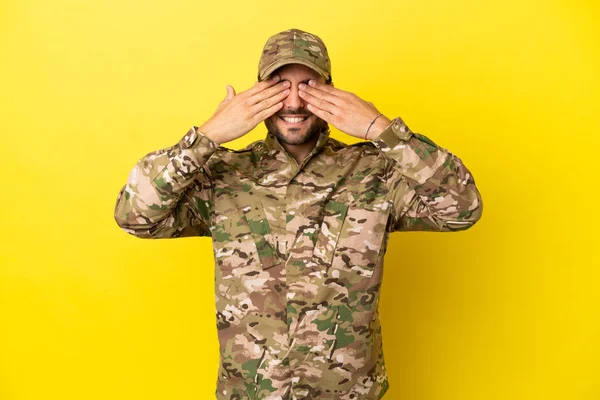 Sarı arka planda izole edilmiş asker gözleri elleriyle kapatıyor.