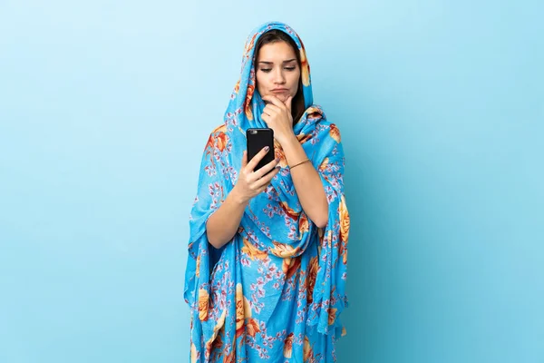 穿着传统服装的年轻摩洛哥妇女被隔离在蓝色背景的思维中 并传达了一个信息 — 图库照片