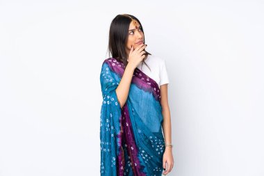 Beyaz arka planda izole edilmiş genç bir Hintli kadının şüpheleri var ve kafası karışmış bir yüz ifadesi var.