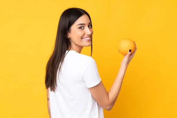 Ung Kaukasiska Kvinna Som Håller Orange Över Isolerad Gul Bakgrund — Stockfoto