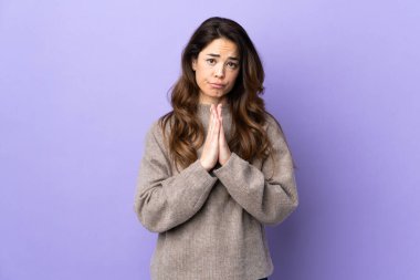 İzole edilmiş mor arka planı olan kadın avuç içlerini bir arada tutuyor. İnsan bir şey ister.