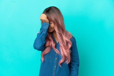 Pembe saçlı, mavi arka planda, baş ağrısı olan, melez, genç bir kadın.