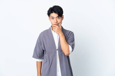 Genç Çinli adam beyaz arka planda izole edilmiş düşünüyor.