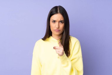 İzole edilmiş arka planda genç beyaz kadın hayal kırıklığına uğramış ve ön tarafı işaret ediyor.