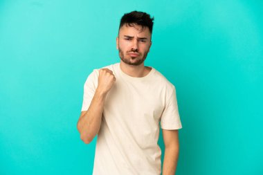 Mutsuz bir ifadeyle mavi arka planda izole edilmiş genç beyaz bir adam.