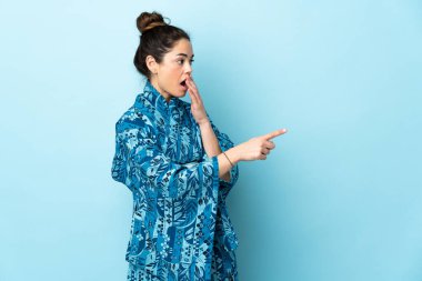Woman wearing kimono over isolated background with surprise expression while pointing side