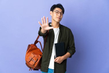 Mor arka planda izole edilmiş genç bayan parmaklarıyla beşi sayıyor.