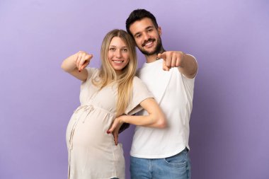 Genç çift hamile ve cepheyi işaret ediyorlar.