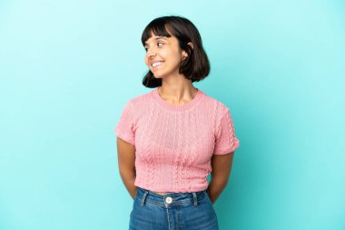 Mavi arka planda soyutlanmış genç melez bir kadın.