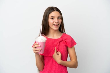 Çilekli milkshake ile izole edilmiş beyaz arka planı olan küçük bir kız. Sürpriz bir yüz ifadesi var.