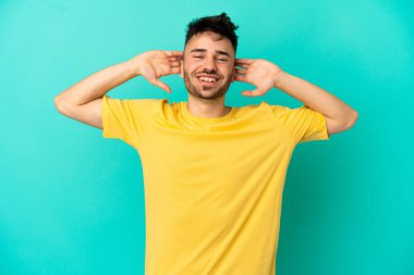 Kafkasyalı genç adam mavi arka planda tek başına gülüyor.