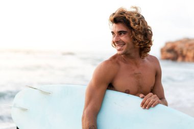 Kafkasyalı genç adam gün doğumunda sörf yapmak için erken kalkar.