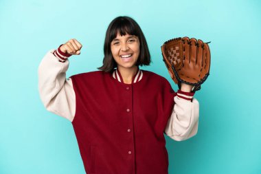 Beyzbol eldivenli, mavi arka planda izole edilmiş genç, melez bir kadın güçlü bir jest yapıyor.