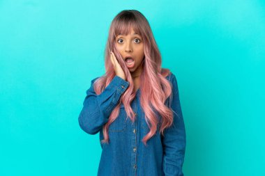 Mavi arka planda pembe saçlı melez bir kadın. Şaşırmış ve şok olmuş bir yüz ifadesi var.