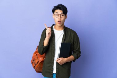 Mor arka planda izole edilmiş genç bir kadın parmak kaldırarak çözümü bulmaya çalışıyor.