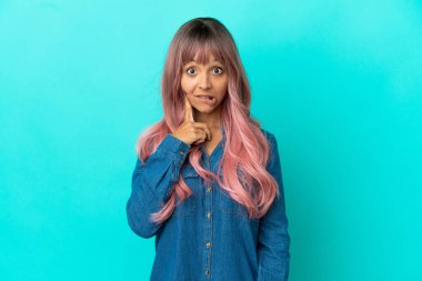 Mavi arka planda pembe saçlı, melez bir kadın.