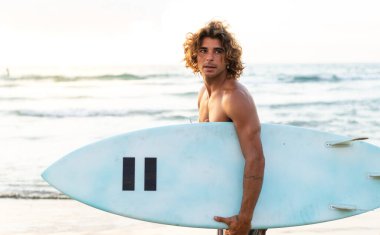 Kafkasyalı genç adam gün doğumunda sörf yapmak için erken kalkar.