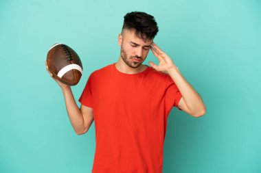 Rugby oynayan beyaz bir adam mavi arka planda baş ağrısıyla izole edilmiş.