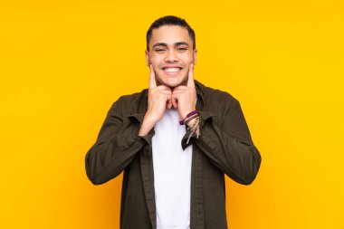 Asyalı yakışıklı adam sarı arka planda izole edilmiş ve yukarı bakıyor.