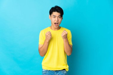 Mavi arka planda izole edilmiş genç bir Çinli kötü bir durum yüzünden hayal kırıklığına uğradı.