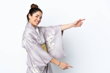 Kimono giymiş bir kadın izole edilmiş arka planda parmak göstererek bir ürün sunuyor.