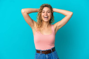 Genç sarışın kadın mavi arka planda yalnız gülüyor.