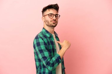 Genç beyaz adam pembe arka planda soyutlanmış gururlu ve kendini beğenmiş.