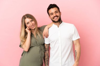 Hamile kadın ve erkek soyutlanmış pembe arka plan mutlu ve gülüyor.