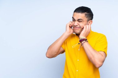 Asyalı yakışıklı adam soyutlanmış arka planda hayal kırıklığına uğramış ve kulaklarını kapatmış