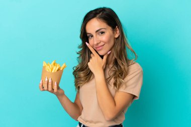Kızarmış cipsleri izole edilmiş arka planda tutan genç kadın mutlu ve gülümsüyor.