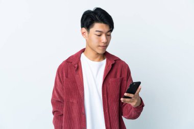 Beyaz arka planda izole edilmiş genç bir Çinli cep telefonuyla mesaj ya da e-posta gönderiyor.