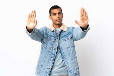 İzole edilmiş beyaz arka plan üzerinde Afrikalı Amerikalı bir adam durdurma hareketi yapıyor ve hayal kırıklığına uğruyor