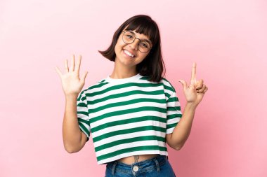 Pembe arka planda izole edilmiş genç melez kadın yediyi parmaklarıyla sayıyor