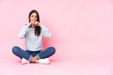 Pembe arka planda izole edilmiş beyaz bir kadın sessizlik işareti gösteriyor.