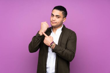 Asyalı yakışıklı adam mavi arka planda izole edilmiş, geç kalma hareketi yapıyor.