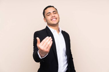 Asyalı iş adamı bej arka planda izole edilmiş. Gelmeye davet ediliyor.