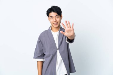 Beyaz arka planda izole edilmiş genç Çinli adam parmaklarıyla beşi sayıyor.