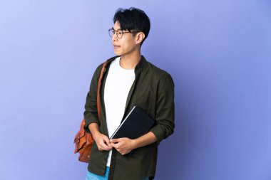 Mor arka planda izole edilmiş genç bir bayan öğrenci.