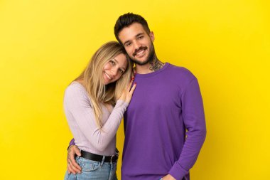 Sarı arka planda yaşayan genç çift gülüyor.