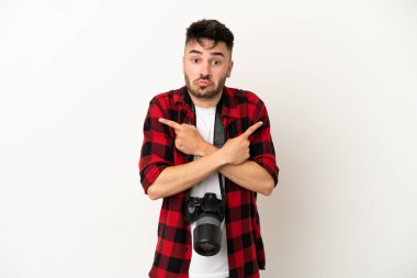 Genç fotoğrafçı beyaz arka planda izole edilmiş beyaz adam yan taraftakilerin şüphelerine işaret ediyor.