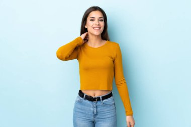 Mavi arka planda izole edilmiş genç beyaz kadın gülüyor.