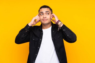 Asyalı yakışıklı adam sarı arka planda yalnız gülüyor.