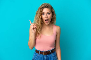 Mavi arka planda izole edilmiş genç sarışın kadın parmağını kaldırarak çözümü anlamaya çalışıyor.