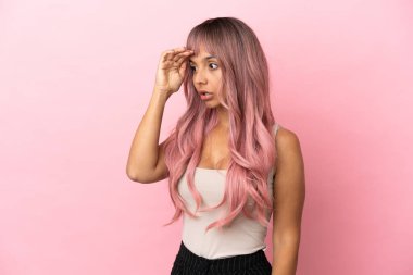 Pembe saçlı melez bir kadın. Pembe arka planda. Sürpriz bir ifadeyle.