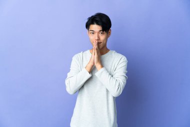 Mor arka planda izole edilmiş genç bir Çinli avuç içini bir arada tutuyor. İnsan bir şey ister.