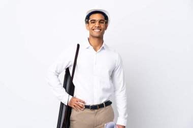 Miğferli Afrikalı Amerikalı mimar, izole edilmiş beyaz arka plan üzerinde planları var. Kolları kalçasında ve gülümsüyor.